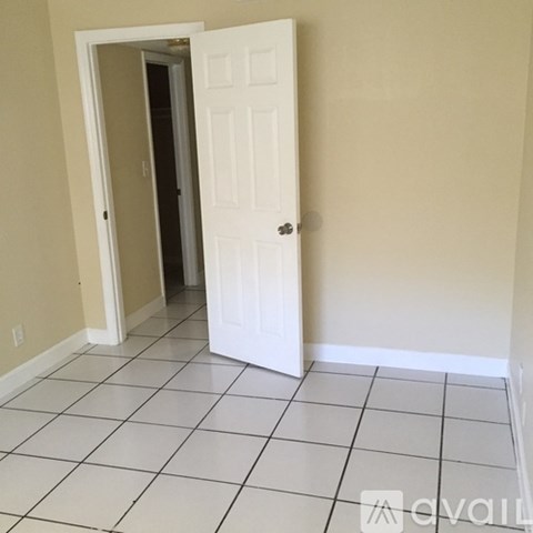 A room with a white door and tiled floor.