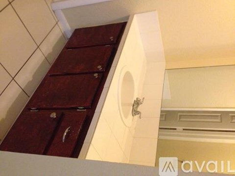 A white bathroom with a brown cabinet and a toilet.