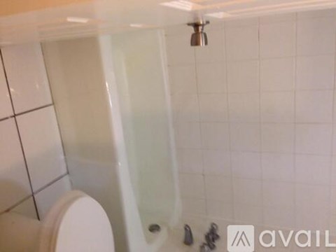 A white toilet in a bathroom with a white tiled wall.