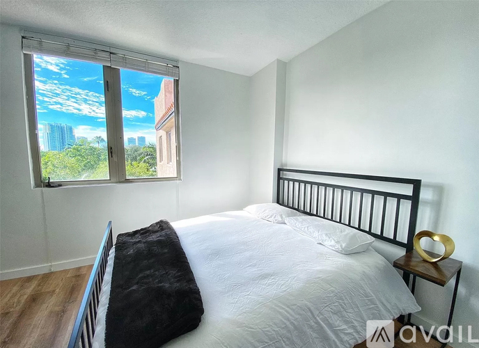 A bedroom with a large bed and a window overlooking a cityscape.