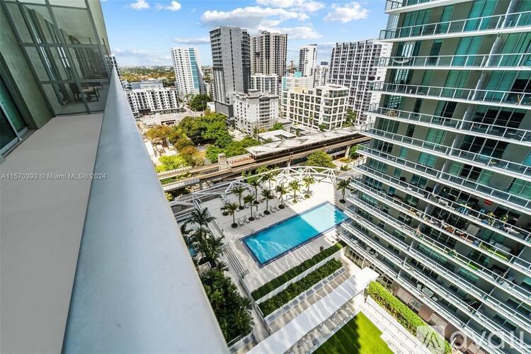 A view from a high-rise building looking down at a pool and greenery.