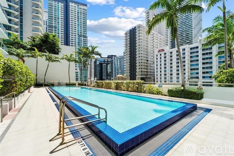 A swimming pool surrounded by palm trees and high-rise buildings.