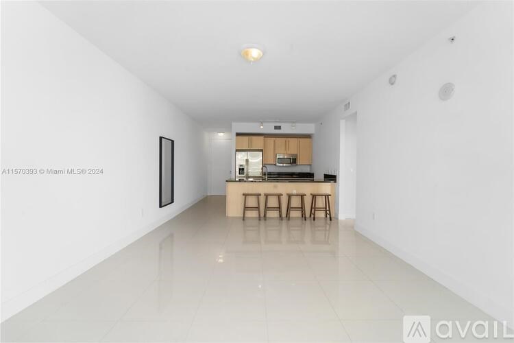 A spacious, white room with a kitchen area in the background.