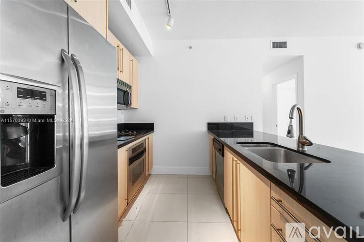 A modern kitchen with a stainless steel refrigerator and wooden cabinets.