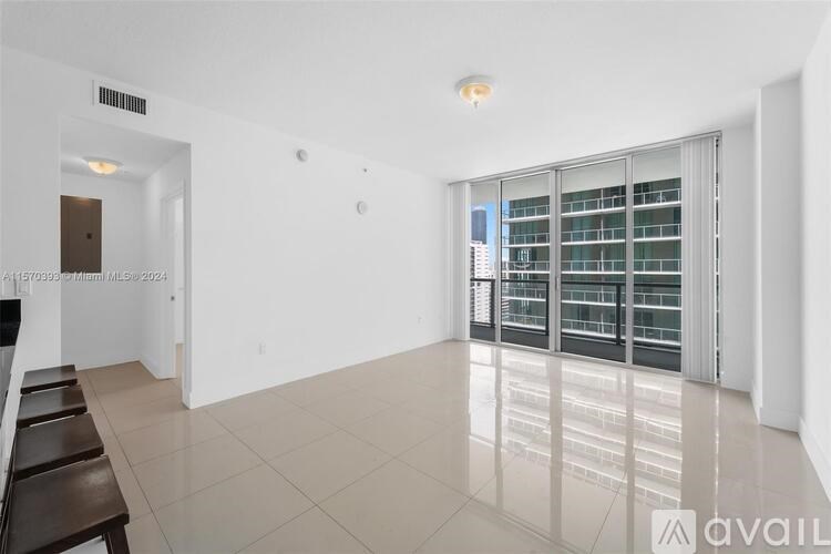 A spacious room with a large window and a view of a city skyline.