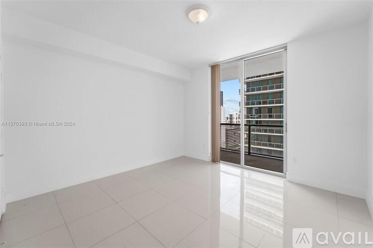 A spacious, empty room with a sliding glass door leading to a balcony.
