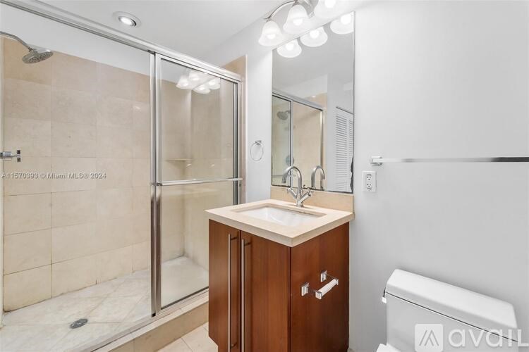 A bathroom with a glass shower door, a sink, and a toilet.