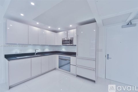 A modern kitchen with white cabinets and a black countertop.
