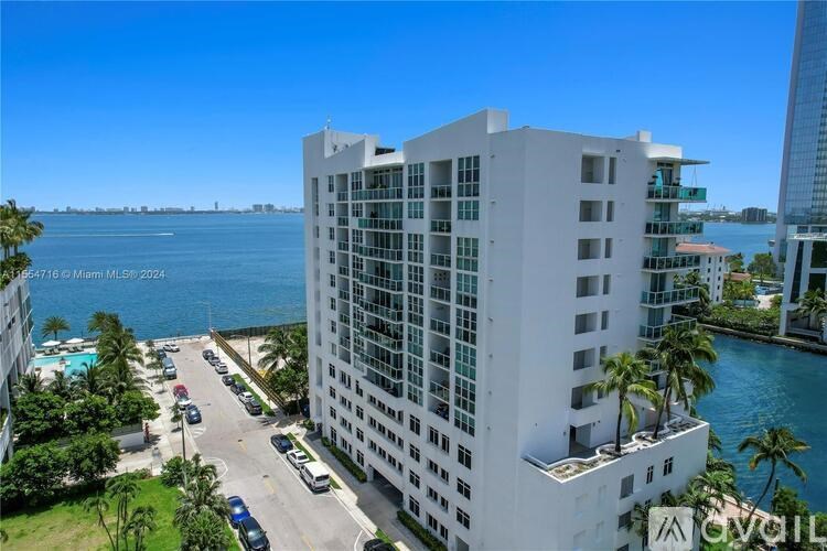 A white building with a glass facade is situated by a body of water.