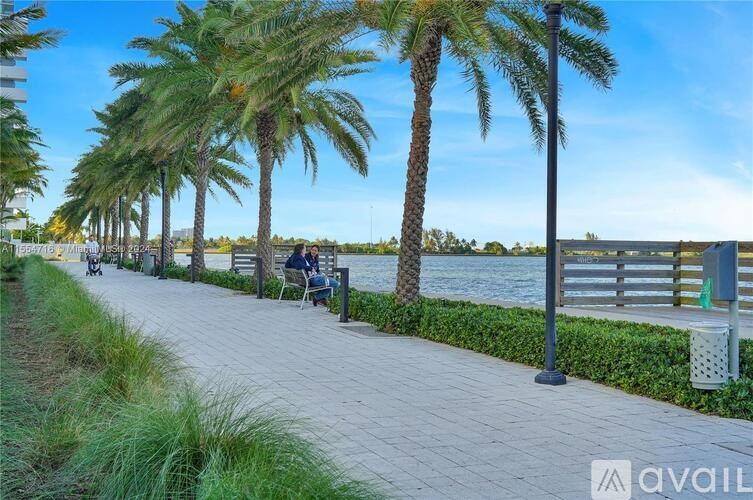 A walkway with palm trees and people sitting on chairs.