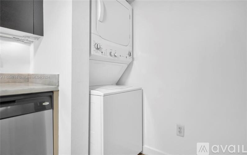 A white dishwasher is mounted on a wall next to a stainless steel oven.
