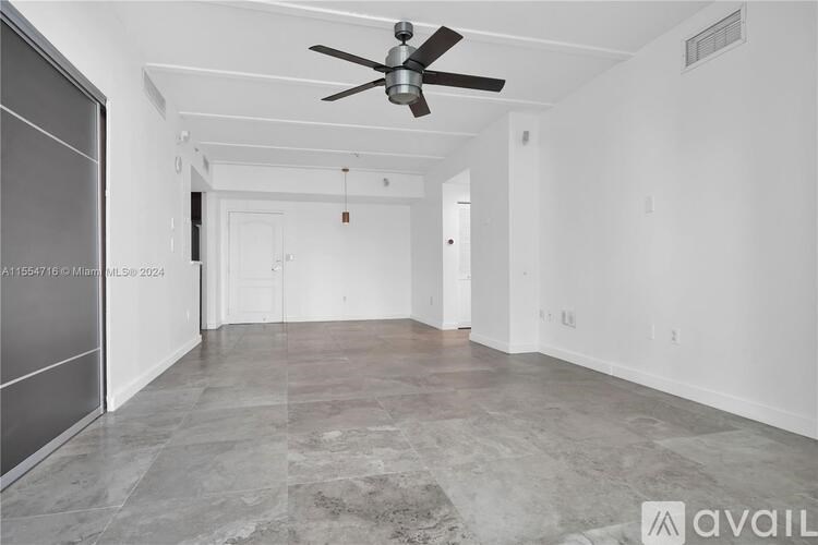 A spacious room with a ceiling fan and marble flooring.