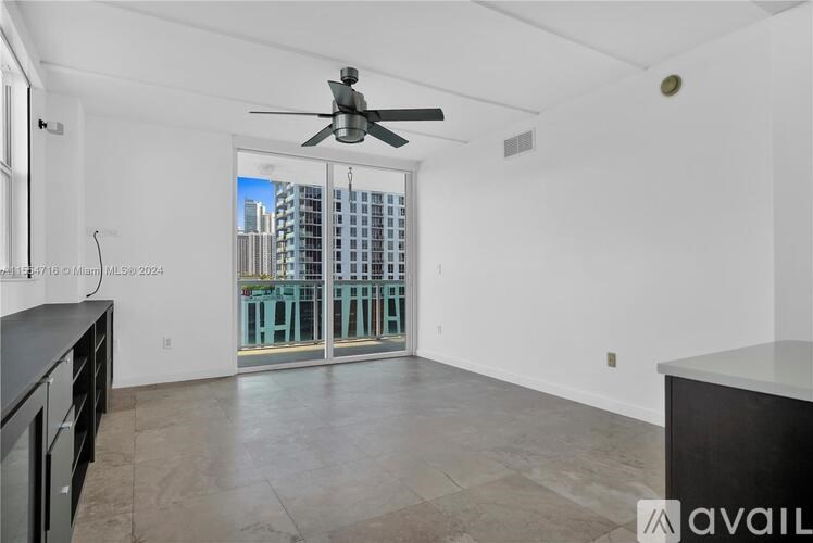 A spacious room with a ceiling fan and a view of a cityscape through the glass doors.