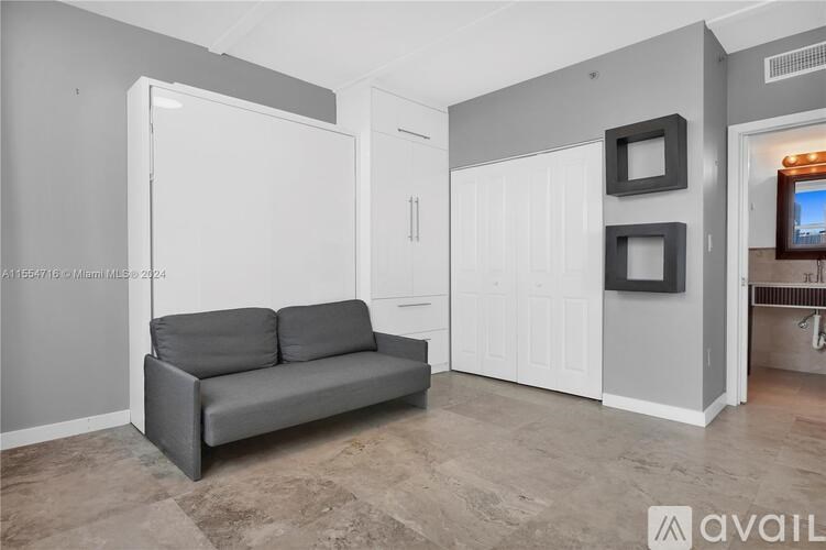 A grey couch sits in a room with a white door and a white cabinet.