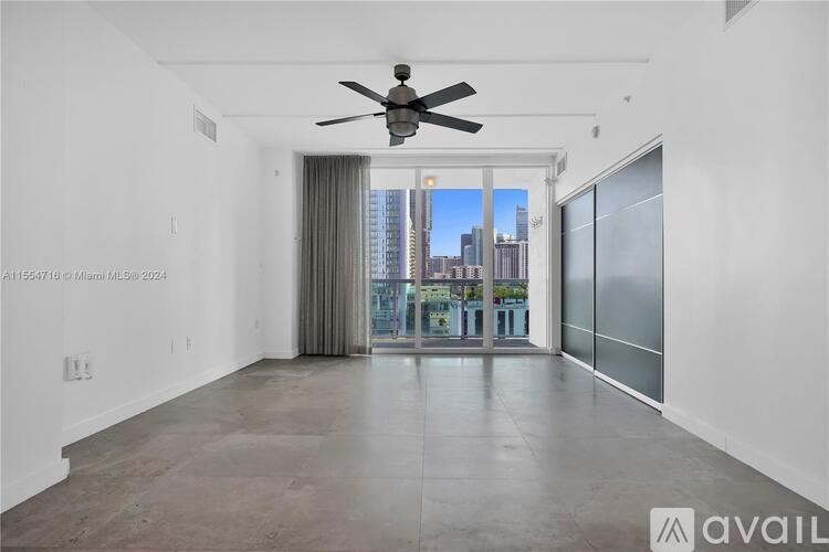 A spacious room with a ceiling fan and a view of the city through the window.