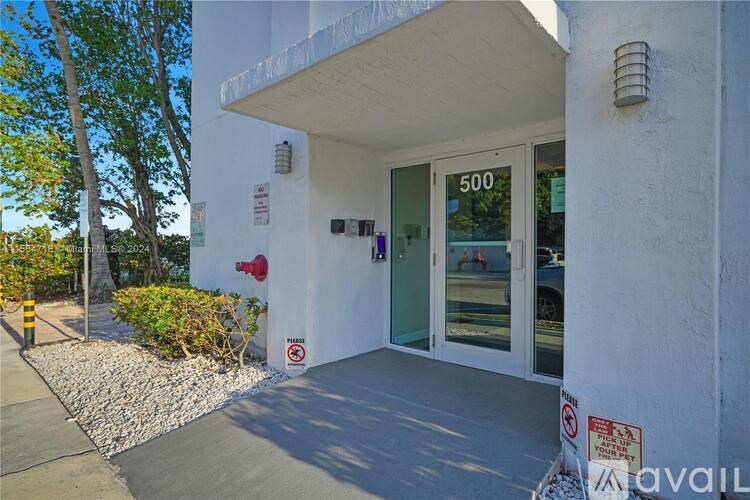 The image shows the front of a building with a white facade and a glass door with the number 500 on it.
