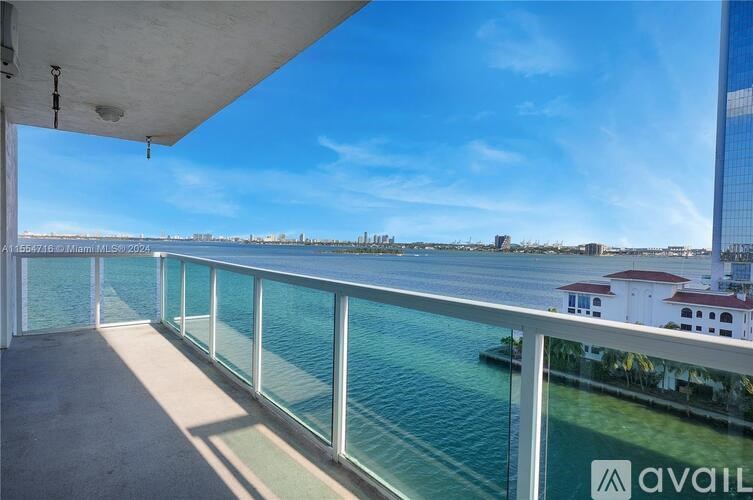 A balcony with a glass railing overlooking a body of water.