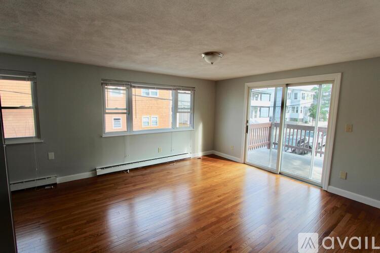 A spacious room with wooden floors and large windows.