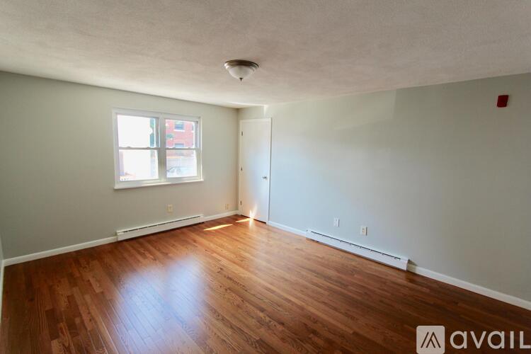 A room with wooden floors and a window letting in light.