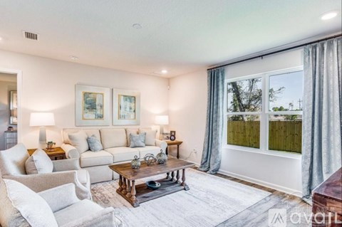 A living room with a white couch, a coffee table, and a painting on the wall.