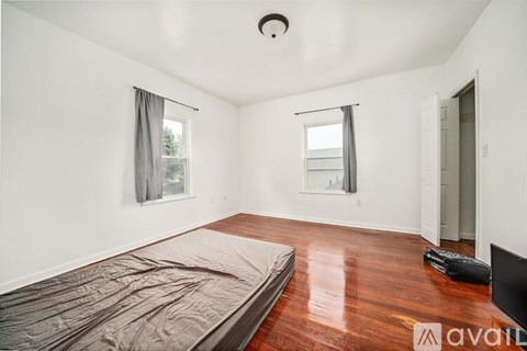 A bedroom with a bed covered in a grey blanket and a television on the right side.