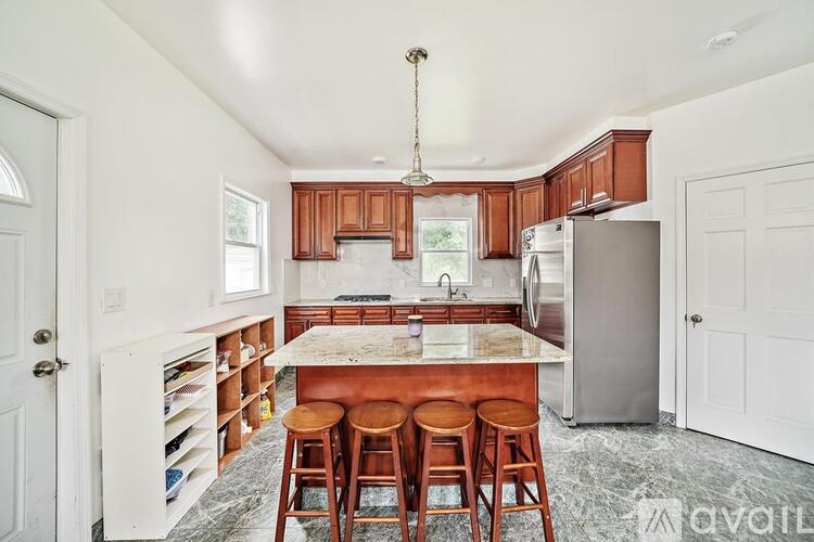 A kitchen with wooden cabinets and a marble island.