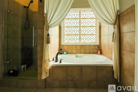A bathroom with a tub and a window with curtains.