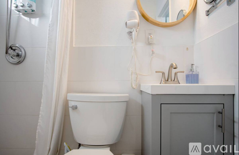 A white toilet is in a bathroom with a white shower curtain.