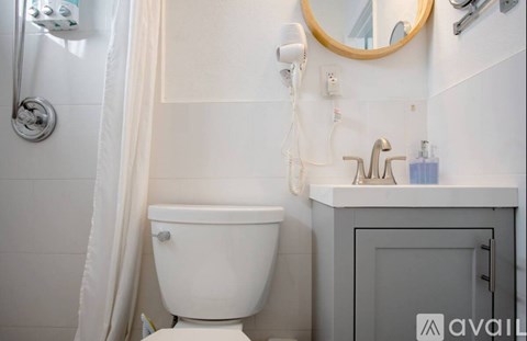 A white toilet is in a bathroom with a white shower curtain.