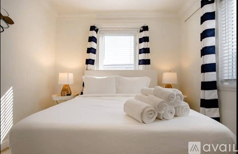A bedroom with a white bed and striped curtains.
