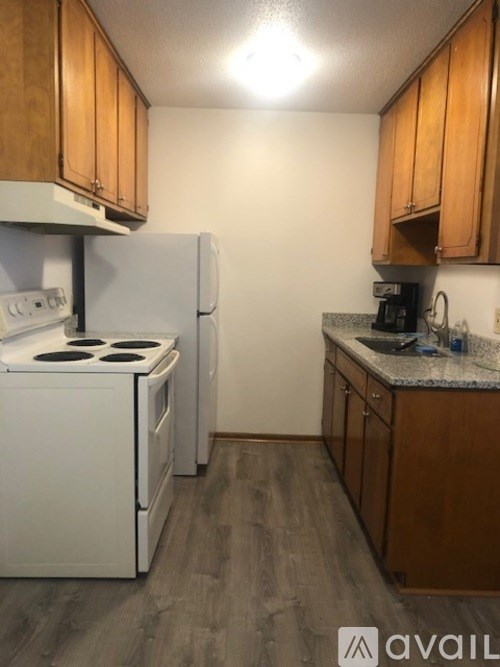 A kitchen with a white stove and refrigerator, wooden cabinets, and a granite countertop.
