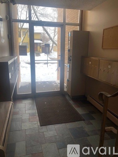 A room with a brown mat on the floor and a refrigerator.