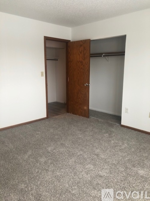 A room with a carpeted floor and a wooden door.