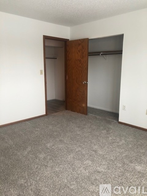 A room with a carpeted floor and a wooden door.