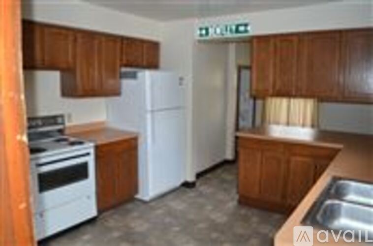 A kitchen with white appliances and wooden cabinets.