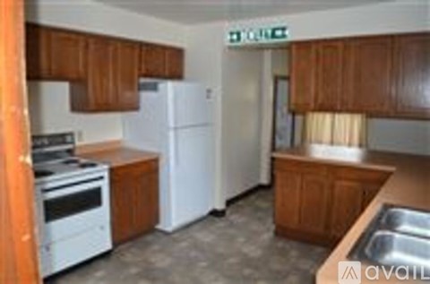 A kitchen with white appliances and wooden cabinets.
