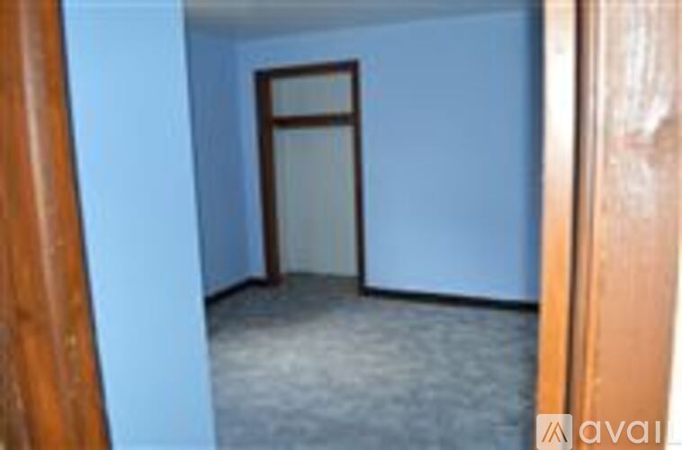 A room with a carpeted floor and a doorway leading to another room.