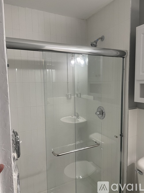 A shower with a glass door and a metal handle.