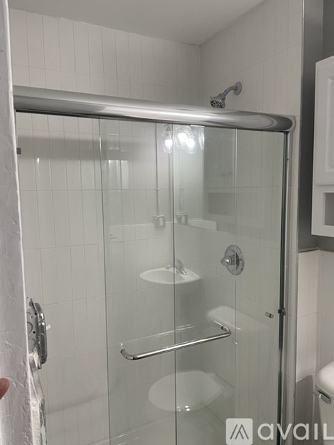 A shower with a glass door and a metal handle.