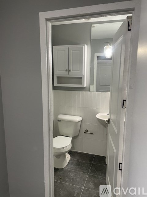 A bathroom with a toilet, sink and mirror.