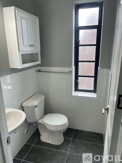 A white toilet sits in a bathroom next to a white sink.