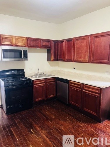 A kitchen with red cabinets and a black stove top oven.