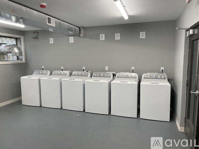 A row of white washing machines are lined up in a laundromat.