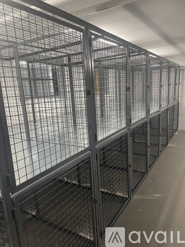 A row of metal cages are lined up in a room.
