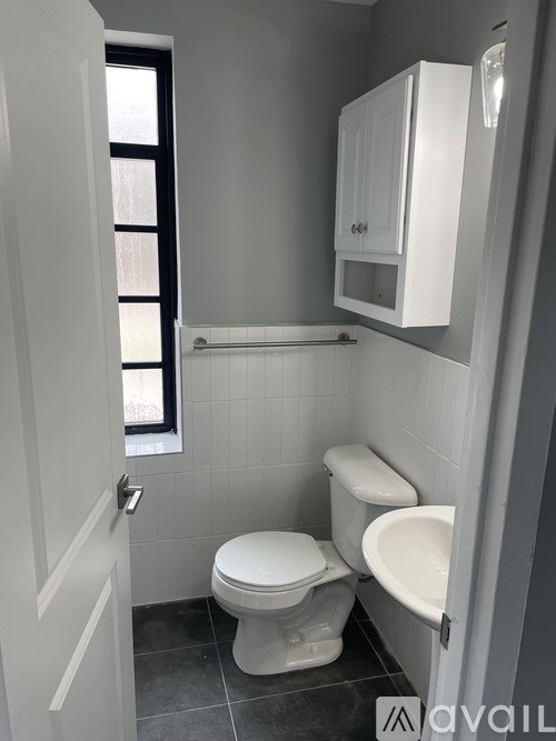 A bathroom with a toilet, sink, and a window.
