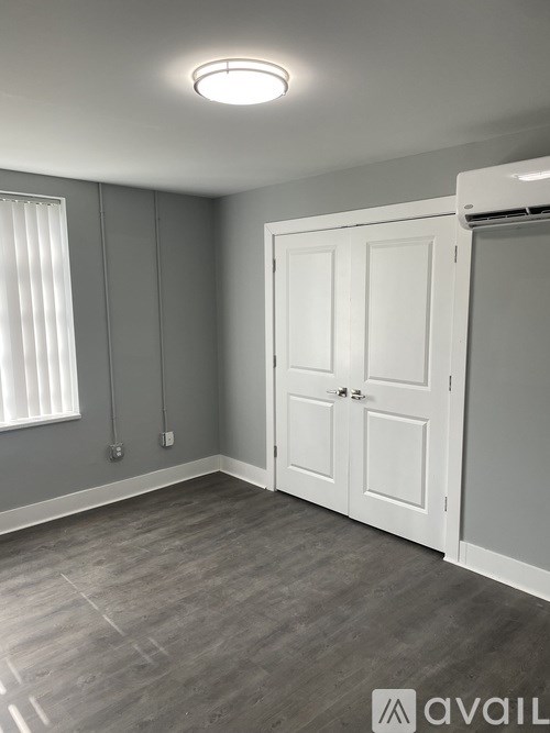 A room with a white door and a window with blinds.