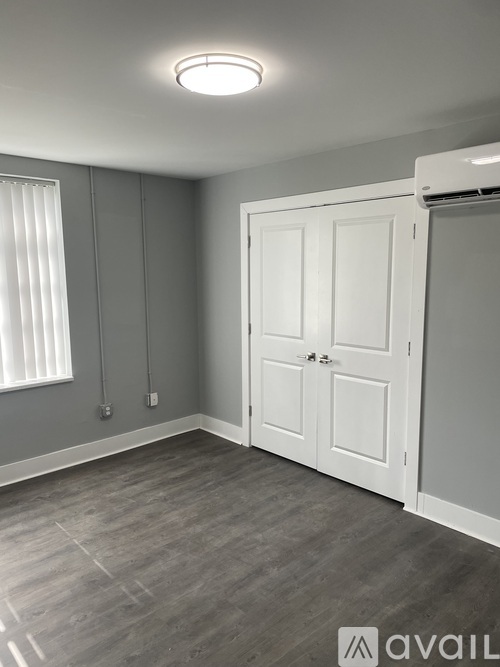 A room with a white door and a window with blinds.