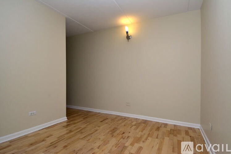 A room with wooden flooring and a single light fixture on the wall.