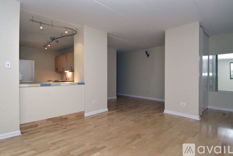 A spacious room with wooden flooring and a bar area.
