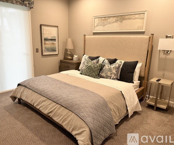 A bedroom with a large bed and a painting on the wall.